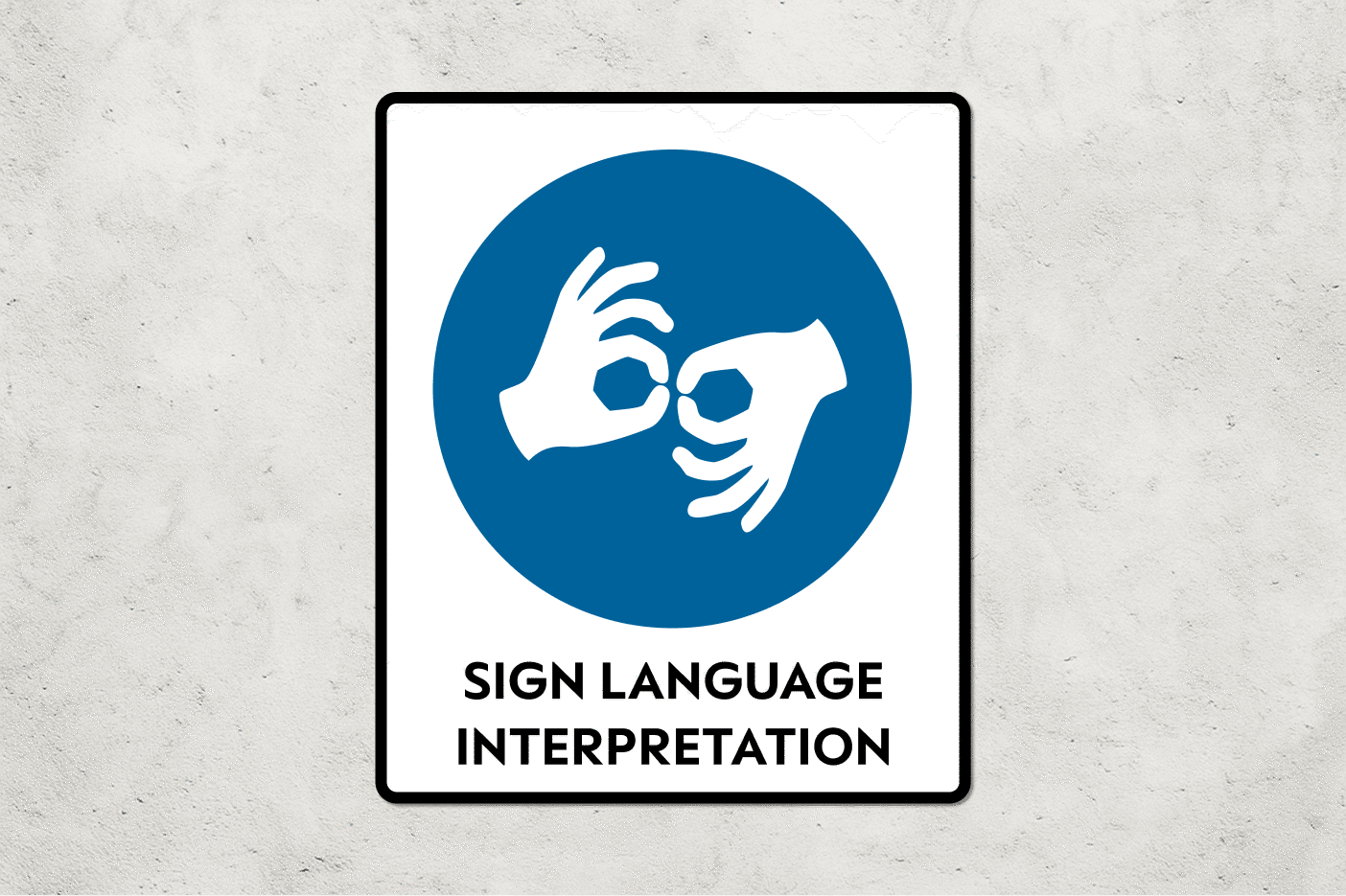 A blue sign on a cement wall that says Sign Language Interpretation with a blue circle with hands signing