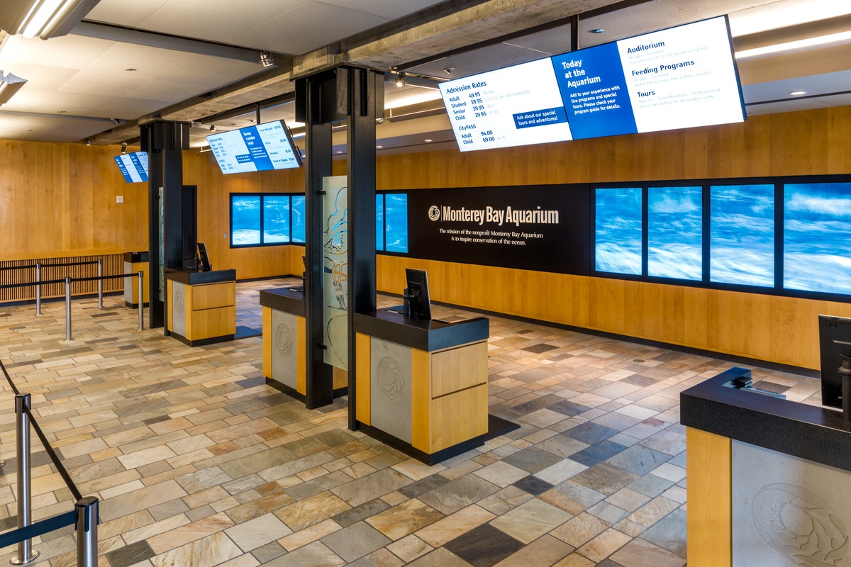 The ticketing area features a beautiful slate floor, five ticketing kiosks, and several flat screens showing admission prices and ocean waves