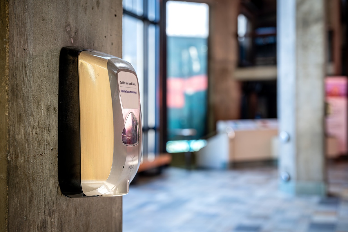 A hand sanitizer dispenser mounted to a concrete pillar in the Aquarium for guest use