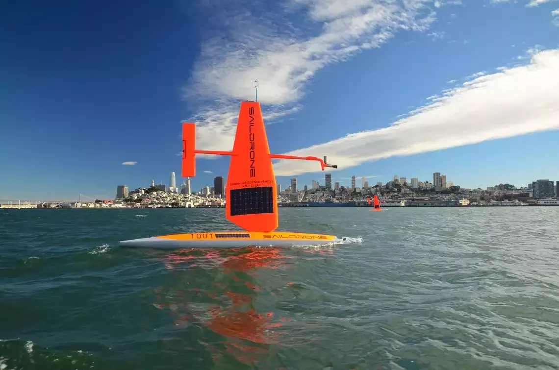 A bright orange oceanographic monitoring tool floats on top of the water just off the coast.