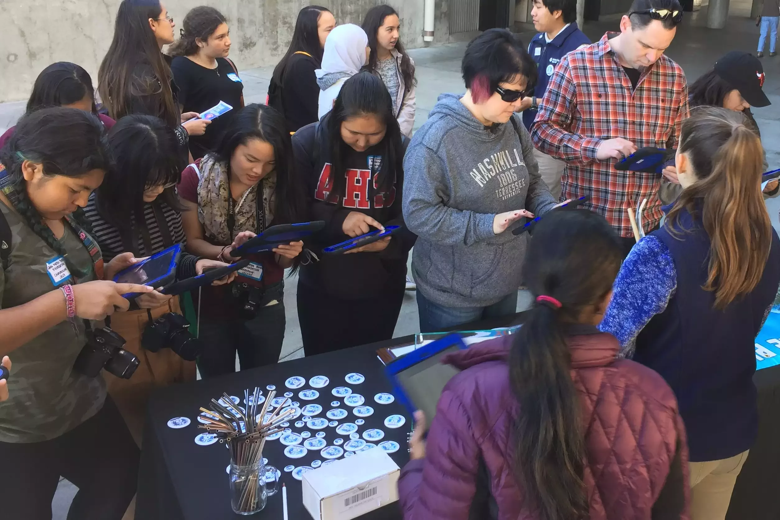 Group of students and adults gathered around a table using signing No Straw November pledge