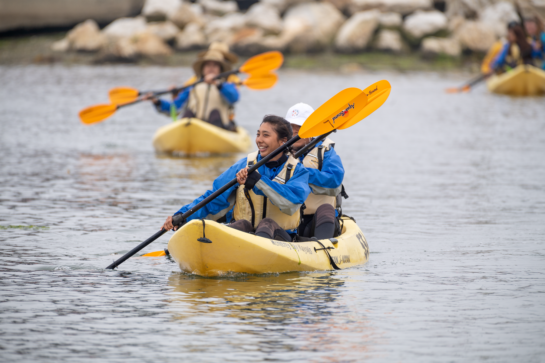 Students kayaking on Elkhorn Slough in two kayaks, paddling across calm water.