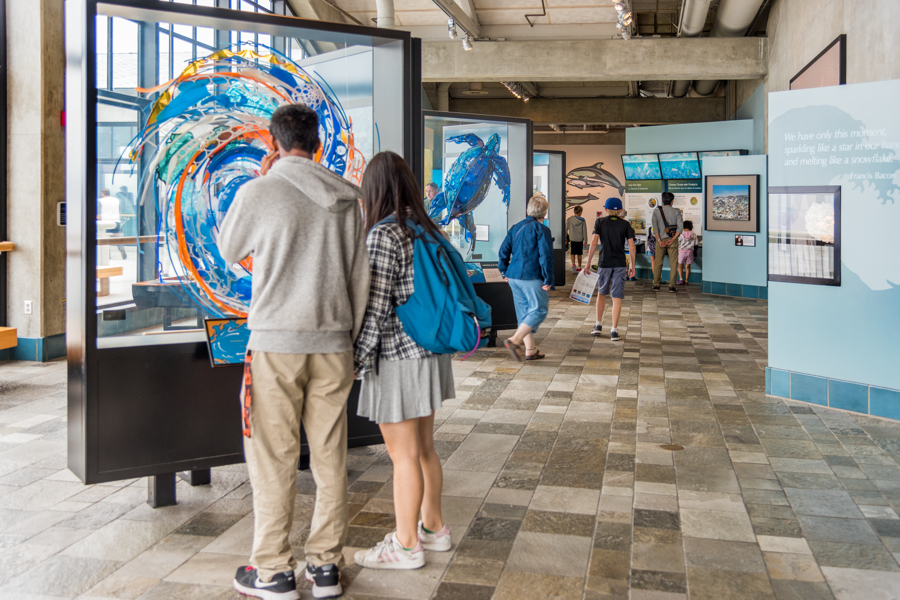 Two visitors observing an art installation made from plastic materials highlighting excessive plastic waste and environmental impact