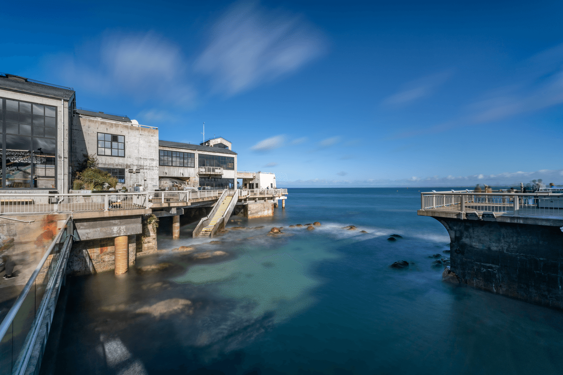 Exterior of the Aquarium building over the water on a clear blue day, ocean visible beneath the deck