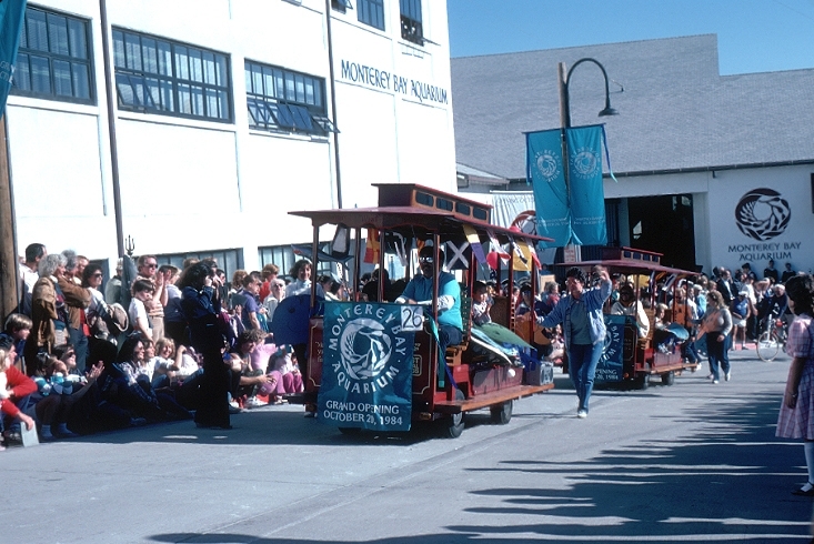 Trolley rolling down the street with crowds celebrating opening day of the aquarium