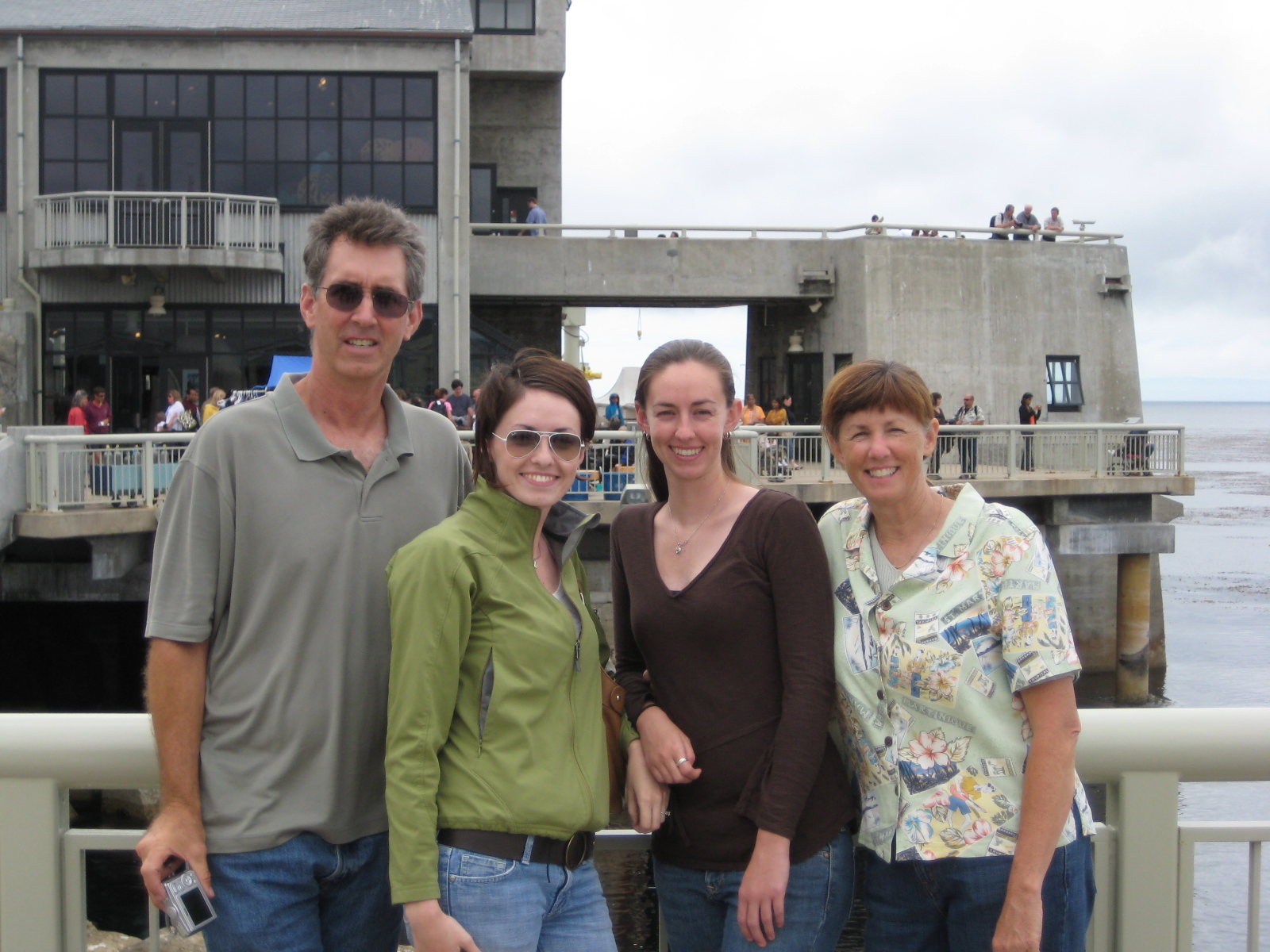 Jess, her sister, and her parents posing together on the back deck of the Monterey Bay Aquarium on an overcast day