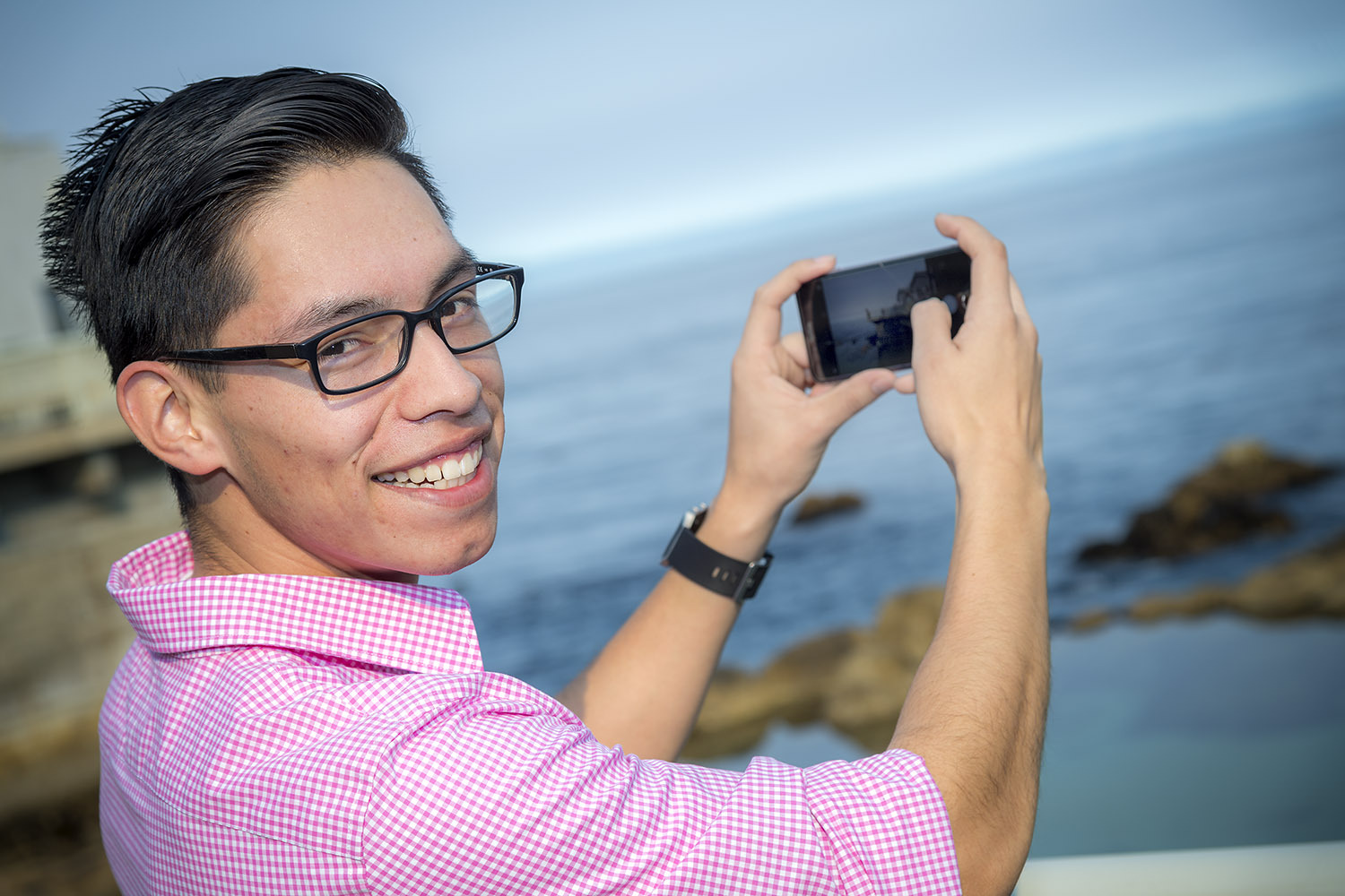 Luis standing with the Monterey Bay in the background taking a selfie