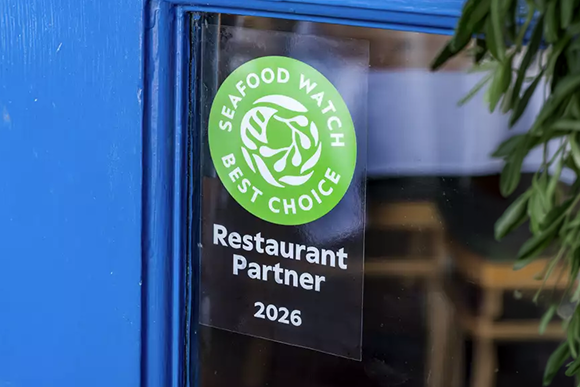 A Seafood Watch Best Choice Restaurant Partner 2026 sticker on a blue restaurant window