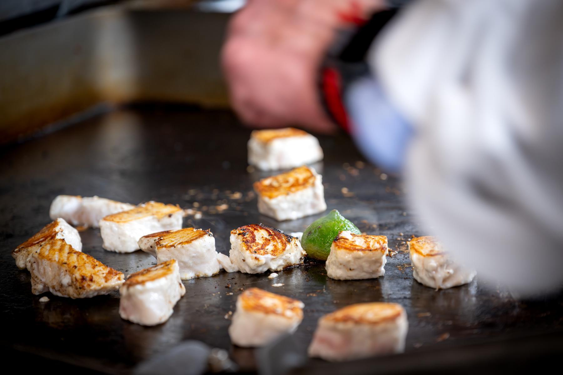 Chefs behind the scenes at Monterey Bay Aquarium kitchen preparing halibut and seafood dishes
