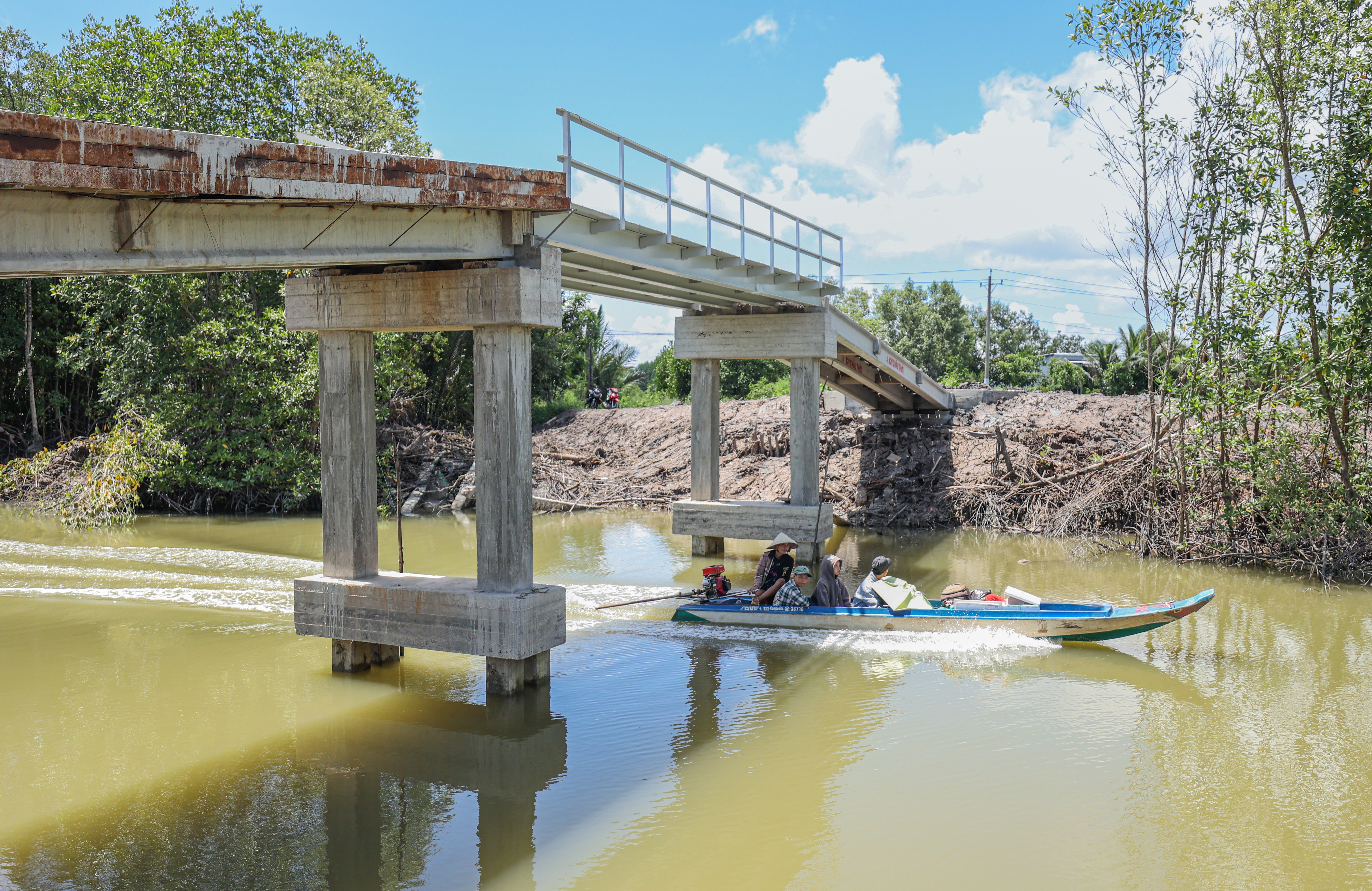 A group of people on a small motorized boat under a new bridge that was built in Vietnam