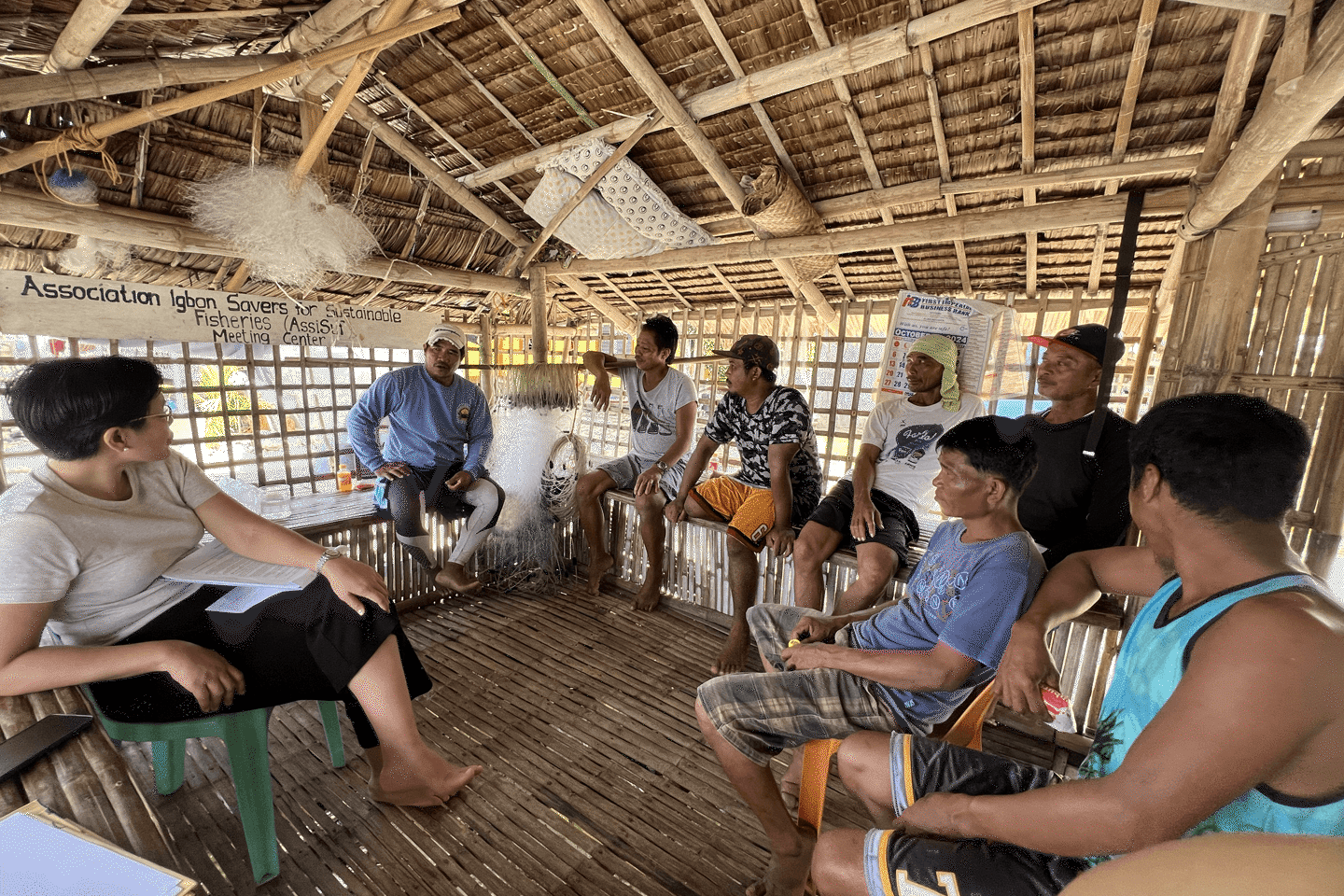 People seated inside a hut meeting about about fishing practices