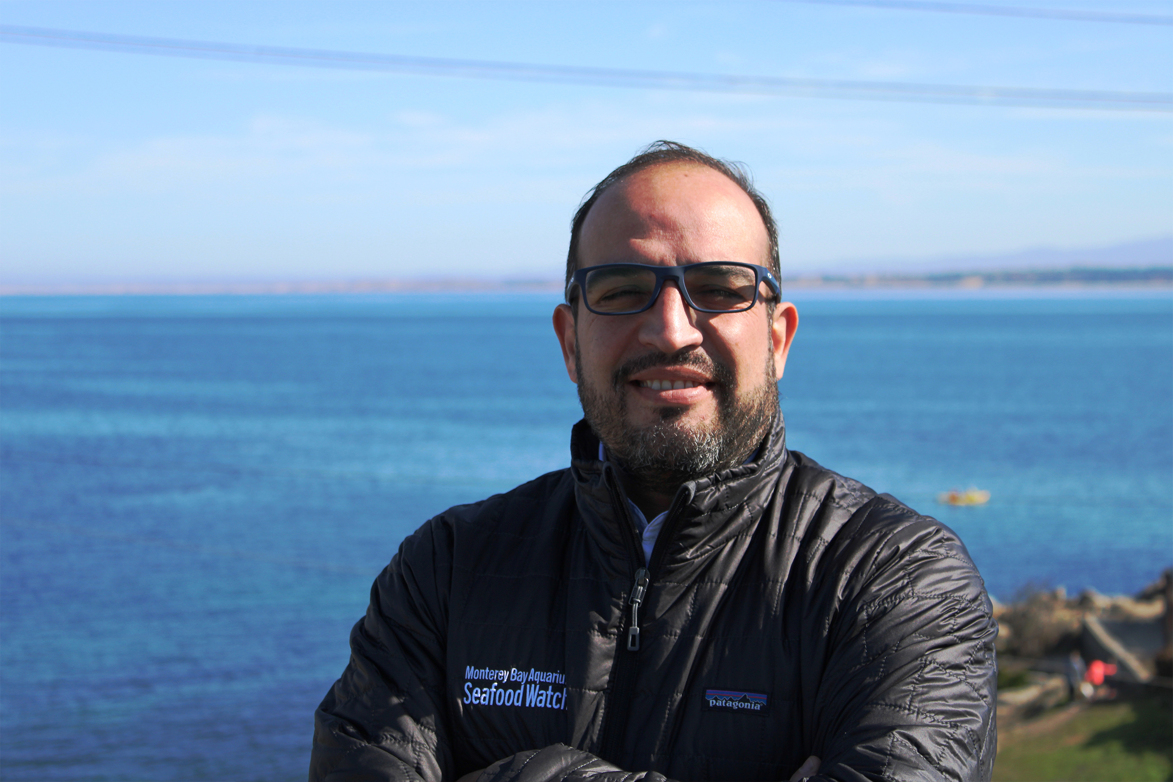 Rolando Ibarra wearing Monterey Bay Aquarium Seafood Watch jacket standing before the ocean