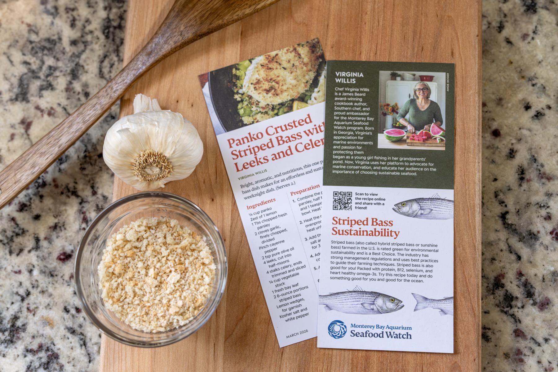 A table with Seafood Watch recipe card for striped bass, garlic and breadcrumbs