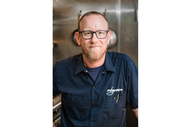 Chef Steve Phelps standing in a restaurant kitchen with stainless steel walls