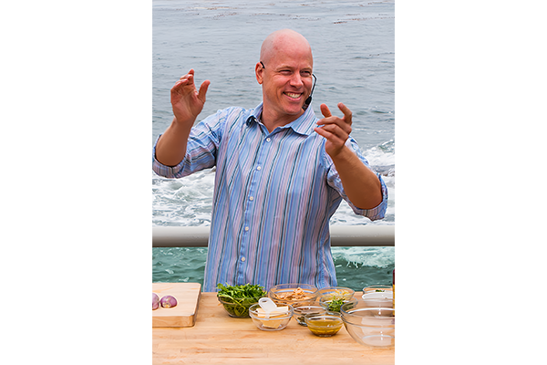 Photo of Nathan Lyon during a cooking demonstration, with the ocean in the background.