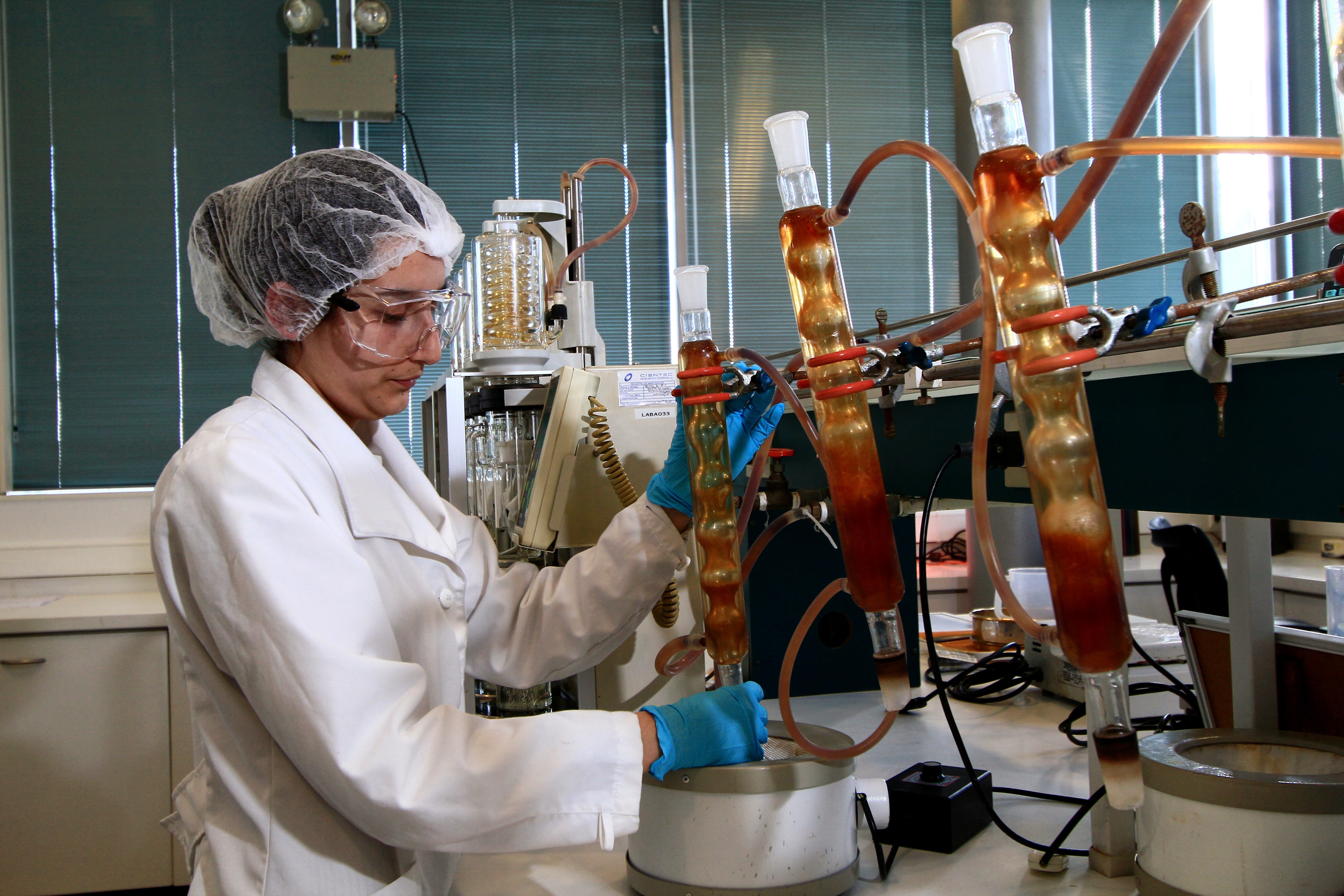 A person in a lab coat testing feed quality in large beakers