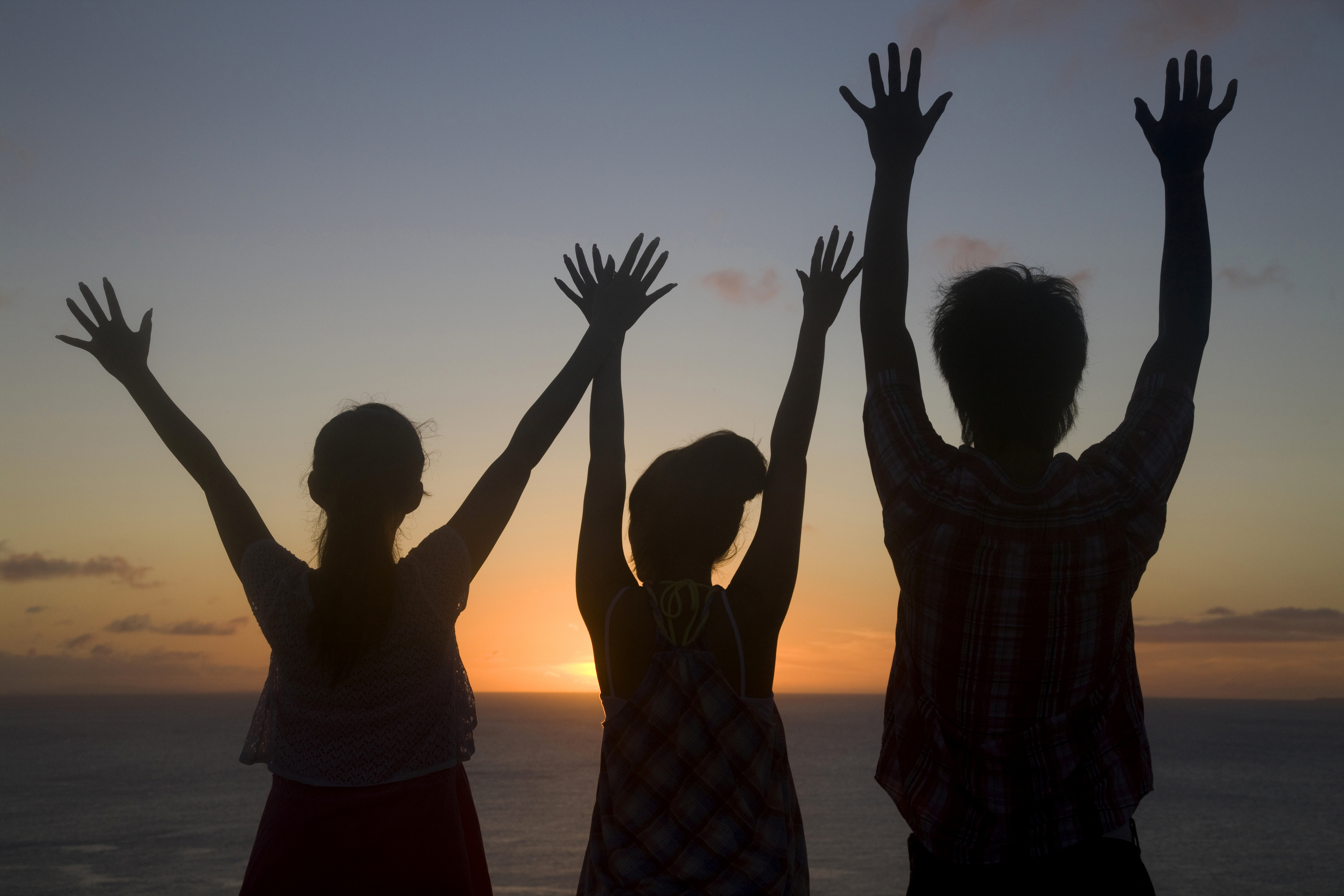 3 people raising their hand in front of a sunset