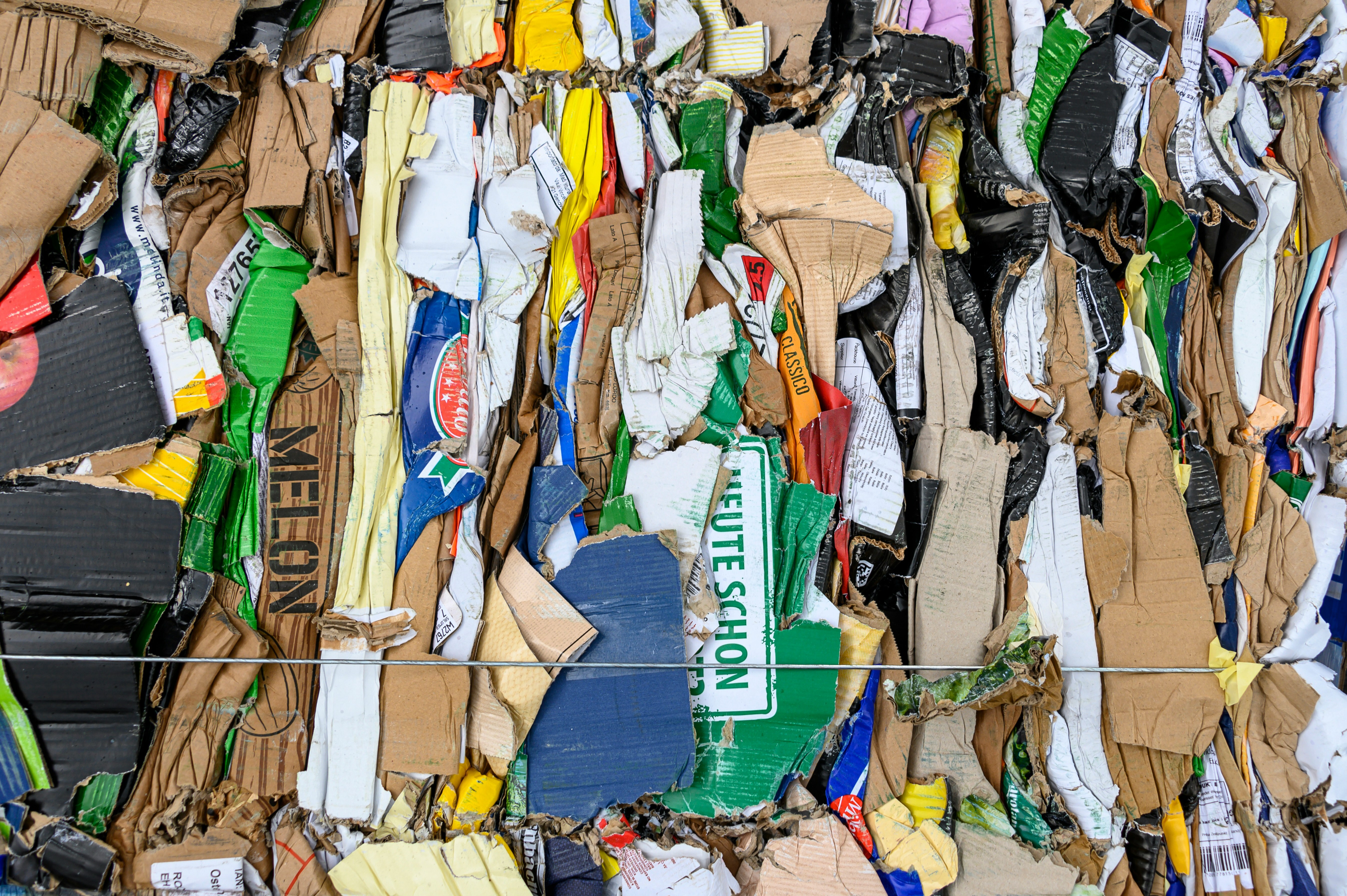 Tightly compressed bales of mixed cardboard and paper materials bound with wire at a recycling facility