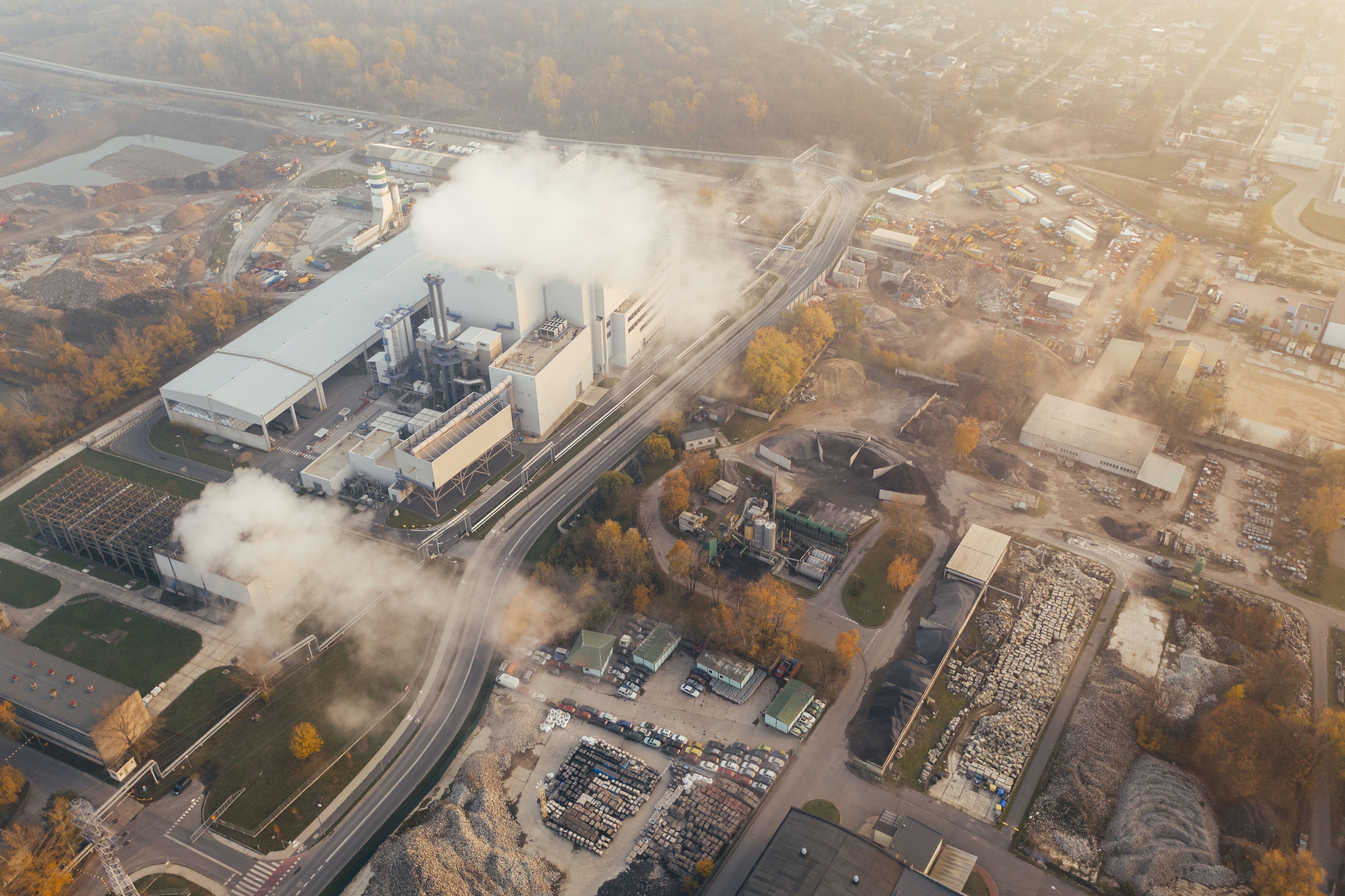Aerial view of an industrial production plant emitting pollution smoke from the stacks.