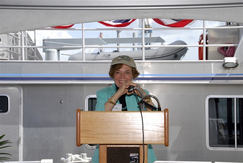 Sylvia on a research boat standing in front of a podium smiling